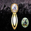 Marque-page en métal bronze style whimsigoth victorien orné d'une théière magique avec motifs floraux,  célestes et étoiles, posé à plat sur un velours noir.
